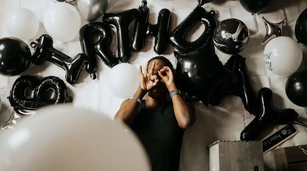 Top view of a man celebrating birthday surrounded by black and white balloons.
